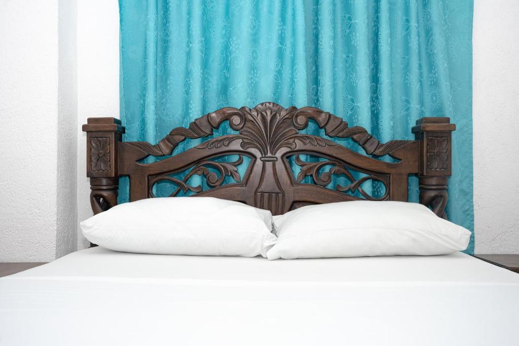 uma cama com uma cabeceira de madeira com almofadas brancas em Hotel La Casa Del Viajero em Cartagena das Índias
