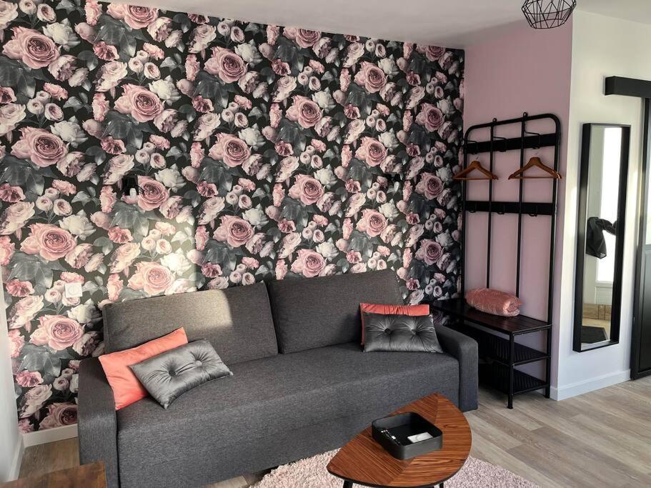 a living room with a couch in front of a floral wall at Le petit Tournebride in Paimpol