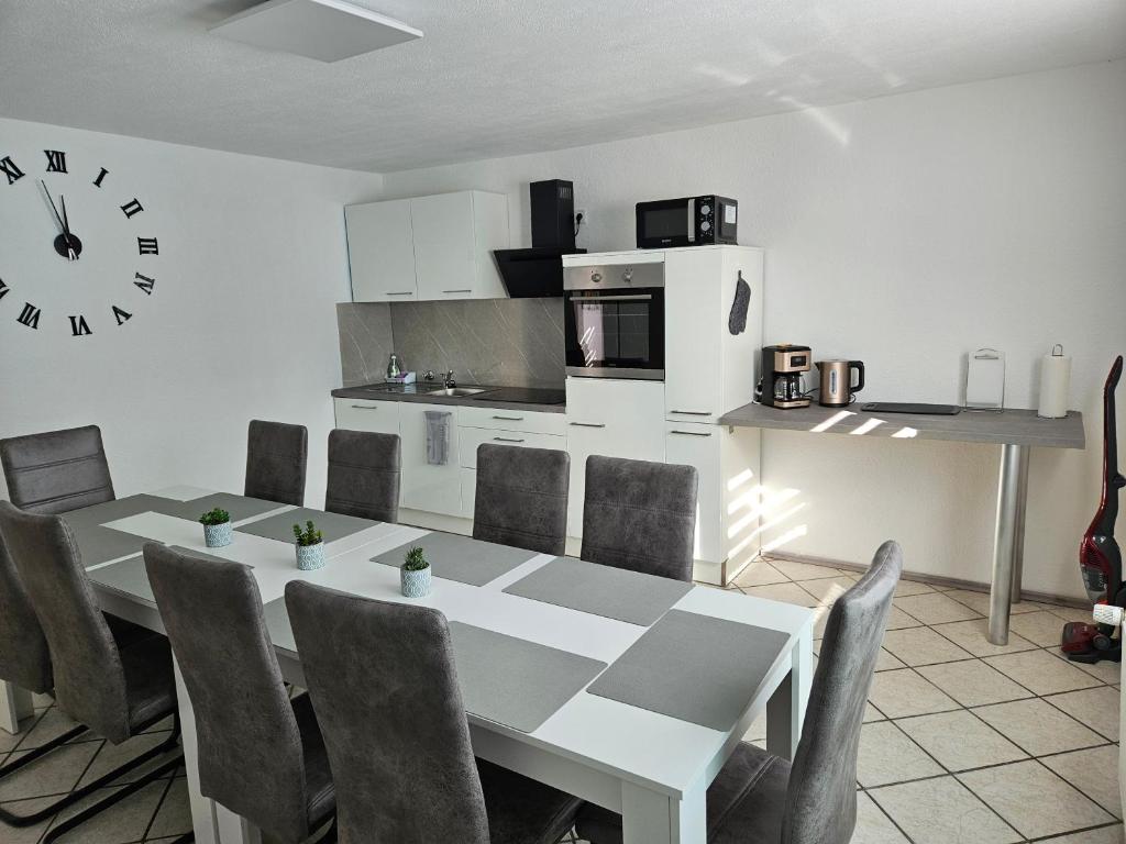 une salle à manger avec une table, des chaises et une horloge dans l'établissement An der Dorfeiche, à Hamm