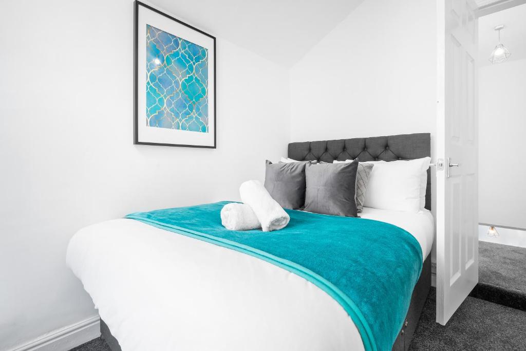 a white bedroom with a bed with a blue blanket at Harborne 2 Bedroom House - Parking - Smart TV - Wifi - 62W in Birmingham