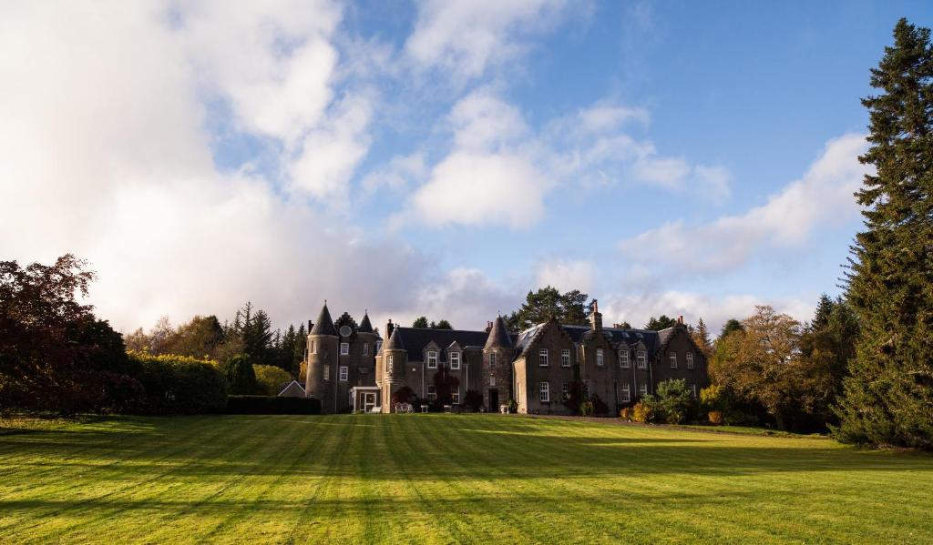 una antigua mansión con un gran campo de césped en Dalmunzie Castle Hotel, en Glenshee