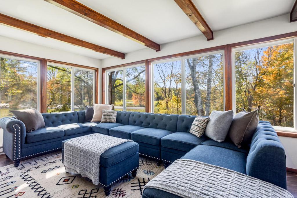 a living room with a blue couch and windows at Catskills Delaware River Modern Colonial Getaway in Narrowsburg