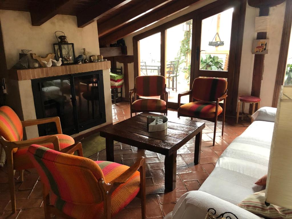 a living room with a fireplace and chairs and a table at La Casa de las Pajaritas in Pasarón