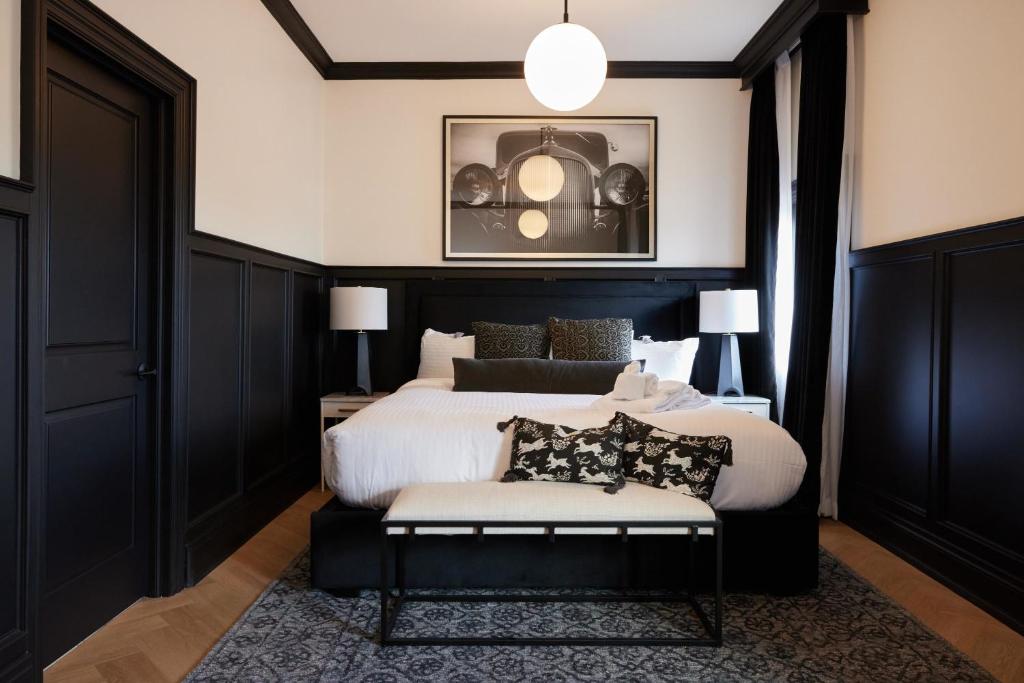 a bedroom with a black and white bed and a chair at The Dorchester Hotel in Collingwood