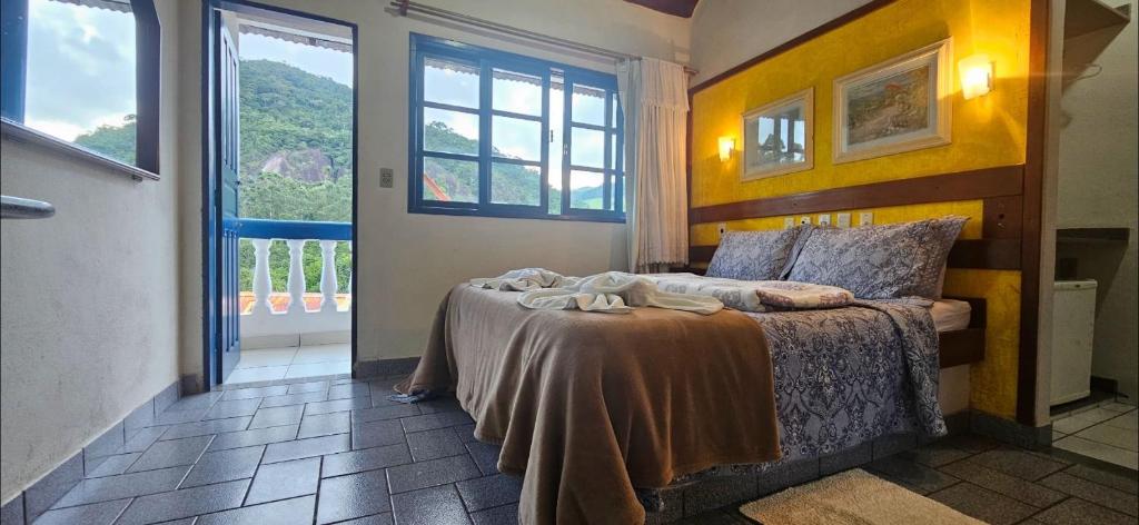 ein Schlafzimmer mit einem Bett und einem großen Fenster in der Unterkunft Pousada Suiça in Santa Leopoldina
