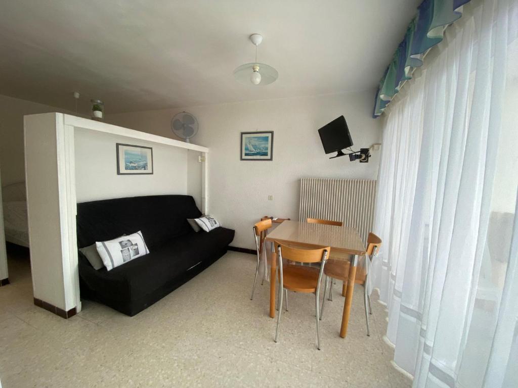 un salon avec un canapé noir et une table dans l'établissement Appartement Climatisé avec Balcon, Parking Privé, Wifi - Proche Thermes et Étang - FR-1-503-23, à Balaruc-les-Bains