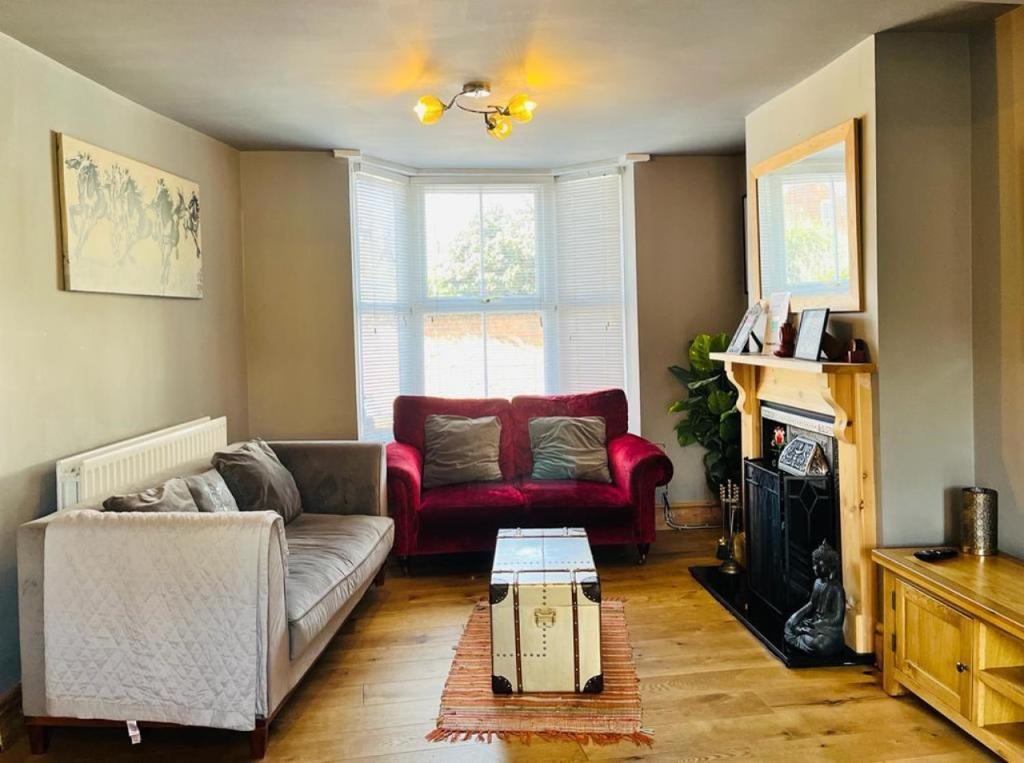 a living room with a couch and a red chair at Bodhi Tree Cottage - Grove Road Cottages in Stratford-upon-Avon