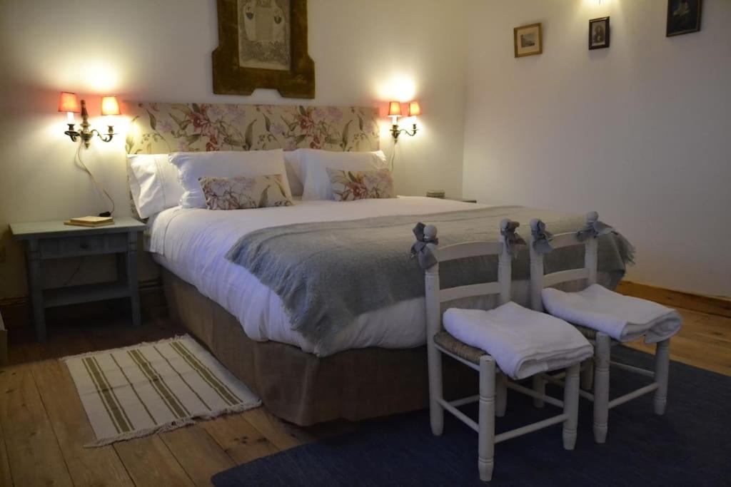 a bedroom with a large bed with two chairs at Casa Valle del Lozoya in Rascafría
