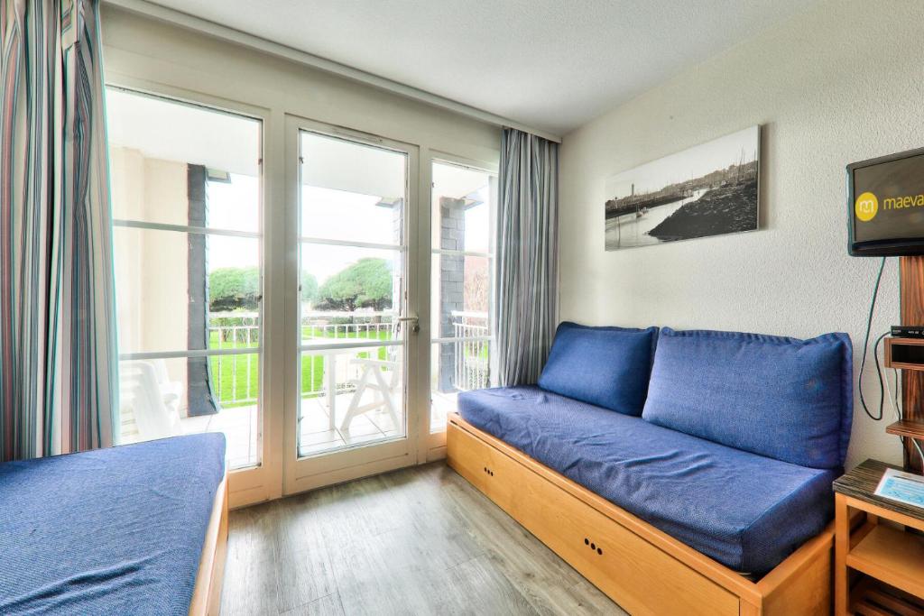 un salon avec un canapé bleu et un balcon dans l'établissement Résidence Port du Crouesty - maeva Home - Appartement 2 pièces 5 personnes - Confort - vue Mer MAE-0564, à Arzon
