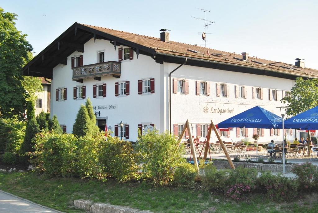 a white building with blue umbrellas in front of it at Landgasthof Goldener Pflug in Frasdorf
