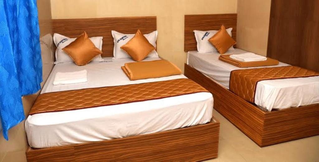 Duas camas individuais num quarto com cortinas azuis em HoteL Namaste London Terminal-2 em Mumbai