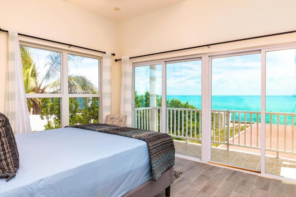 a bedroom with a bed and views of the ocean at Breathtaking Turtle Tail Drive Oceanfront Villa in Providenciales