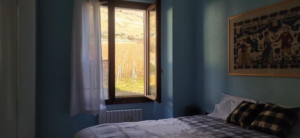 um quarto azul com uma cama e uma janela em Locazione turistica VENTO del NORD em Tirano
