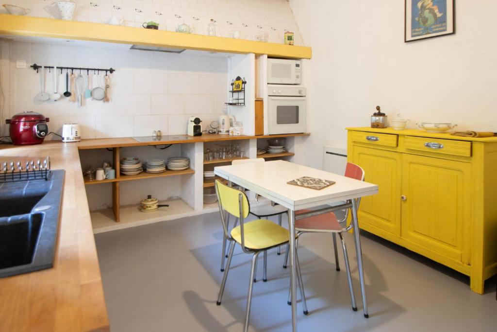 cocina con armarios amarillos, mesa y sillas en Appartement Les Cyprès de l’Île, en Aviñón