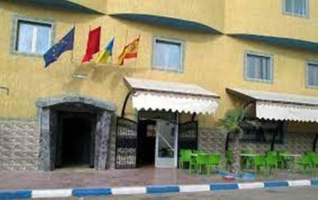 un hotel con mesas verdes y sillas frente a un edificio en RESIDENCE HOTELIERE CANALINA, en Tarfaya