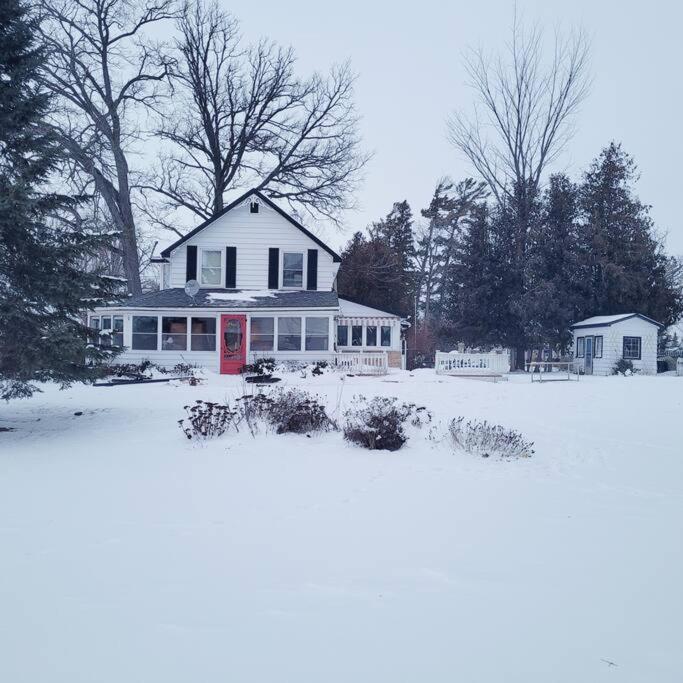 a white house with a red door in the snow at Rosedale Cottage@Baksam lake in Fenelon Falls