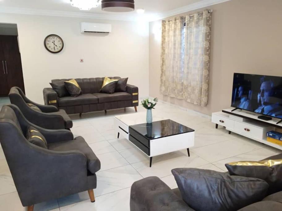 sala de estar con sofás y TV de pantalla plana. en Cozy home in East Legon Hills en Accra