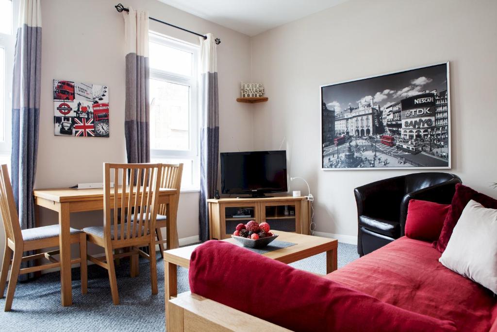 a living room with a red couch and a table at Madison Hill - Bedford Hill 1 - One bedroom flat in London