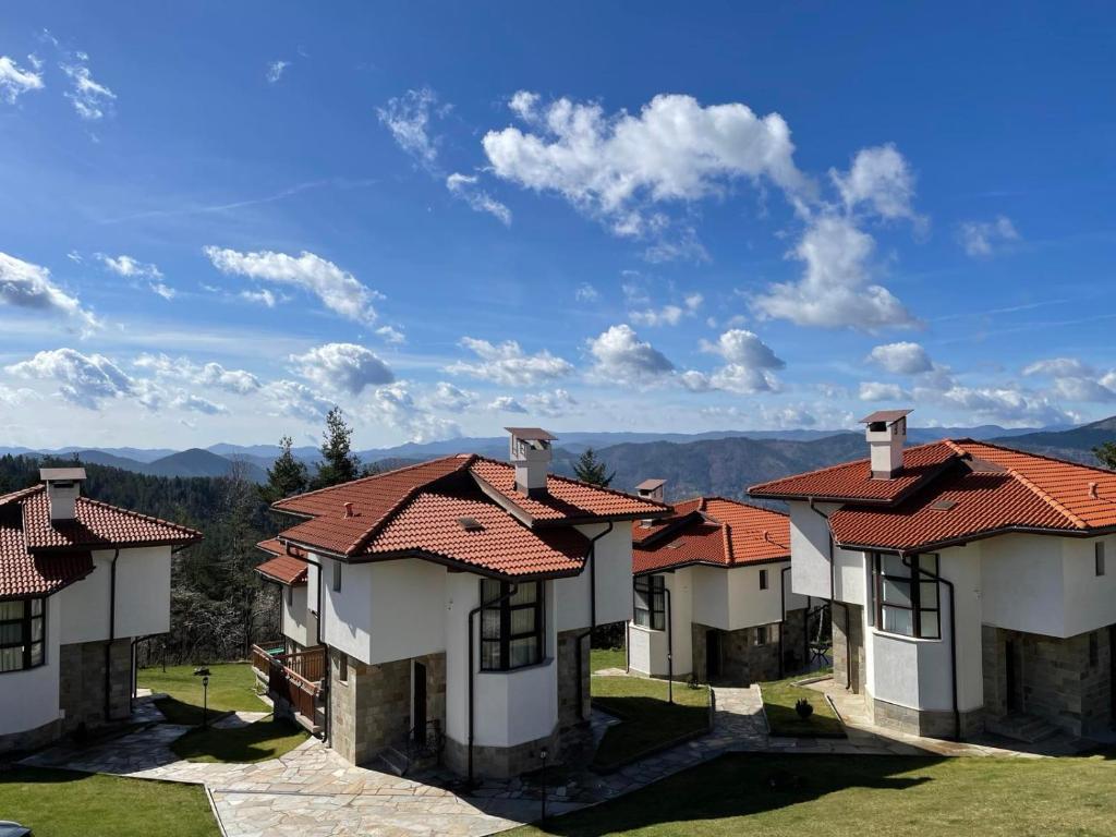 una fila de casas con techos rojos en una colina en Cassiopea Villas en Pamporovo