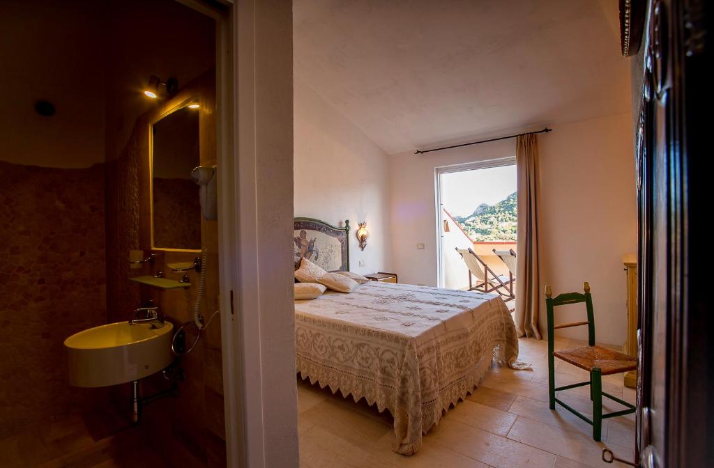 a bedroom with a bed and a bathroom with a window at Antica Dimora La Corona in San Pantaleo