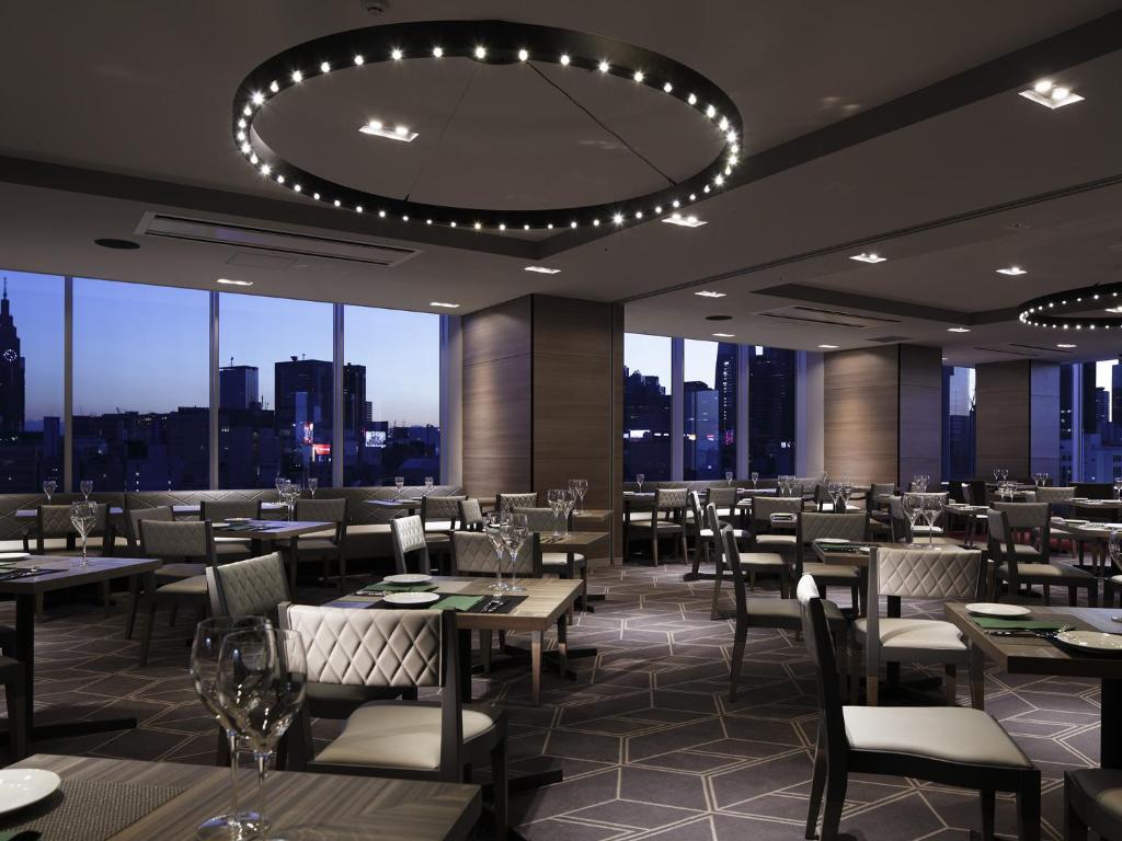 a restaurant with tables and chairs and a large window at Shinjuku Granbell Hotel in Tokyo