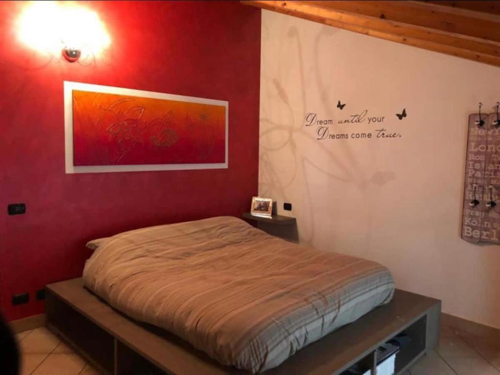Ce lit se trouve dans une chambre dotée d'un mur rouge. dans l'établissement Sweet Home Albino, à Albino