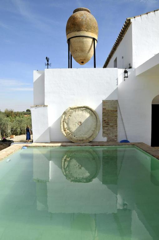 une villa avec une piscine et une horloge dans un bâtiment dans l'établissement SEÑORIO DEL CADOSO, à Carmona