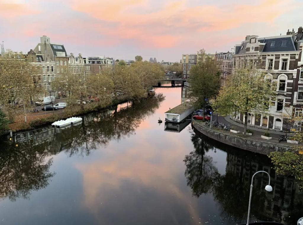un río en una ciudad con edificios y un puente en Canal view home in the center, en Ámsterdam