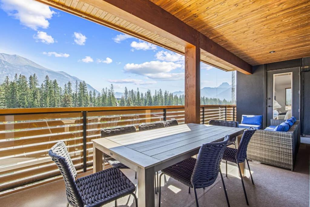 a table and chairs on a balcony with mountains at Serenity Villa at Tamarack in Canmore