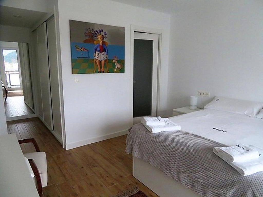 una camera da letto con un letto e un dipinto sul muro di EGONA-ZUM8 Vista espectacular,piscina,tenis,playa a Zarautz