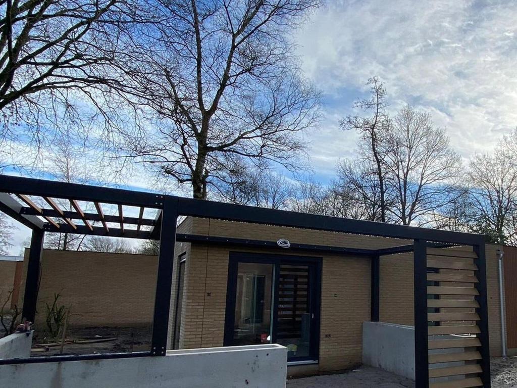 uma pequena casa com um telhado preto e um alpendre em Beautiful holiday home in Voorthuizen em Voorthuizen