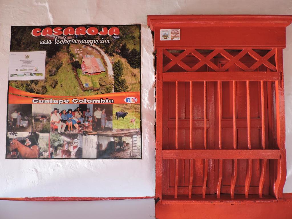 una puerta roja y un cartel en la pared en Casa Roja Parche Campestre - Hospedaje Guatapé, en Guatapé