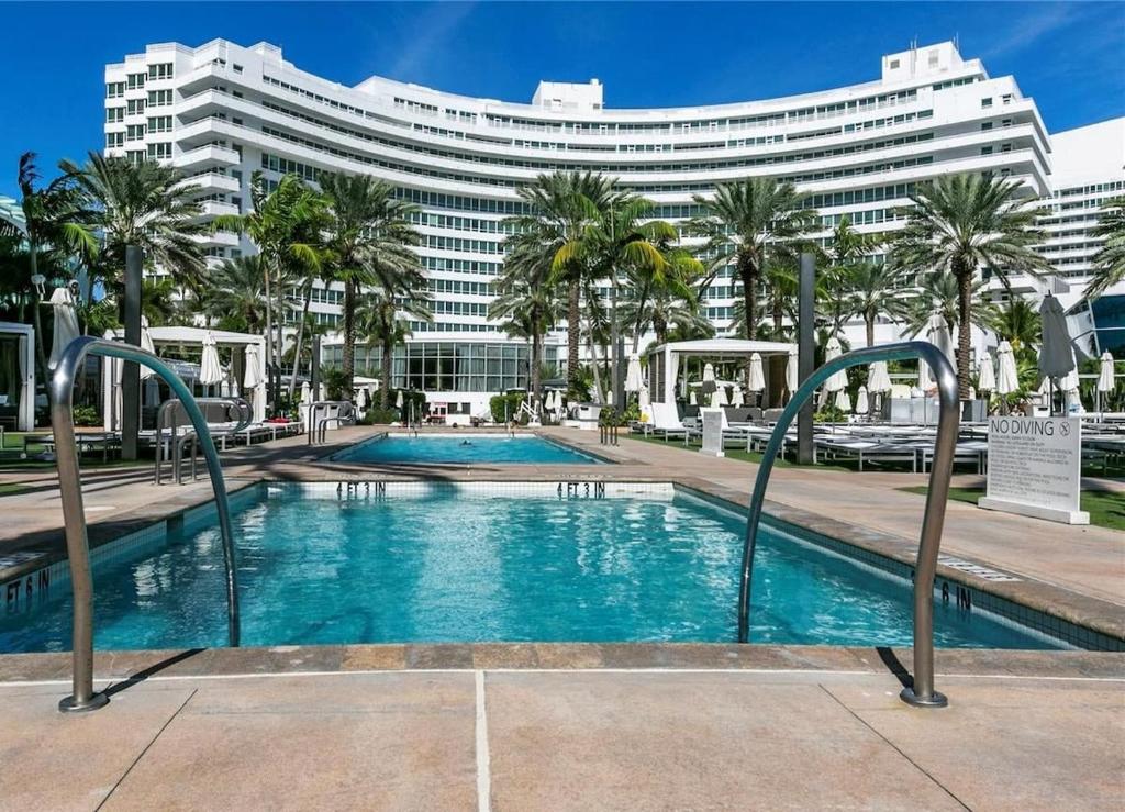 une piscine en face d'un grand bâtiment dans l'établissement FontaineBleau Resort Ocean plus Bay View w Balcony, à Miami Beach