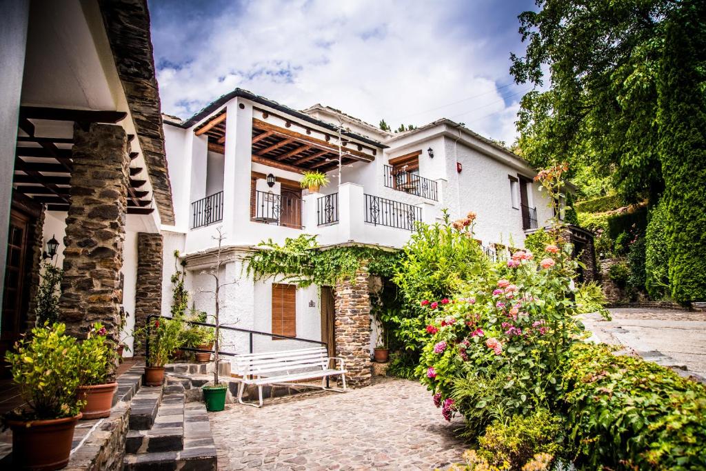 a large white house with flowers in front of it at Finca Los Llanos in Capileira