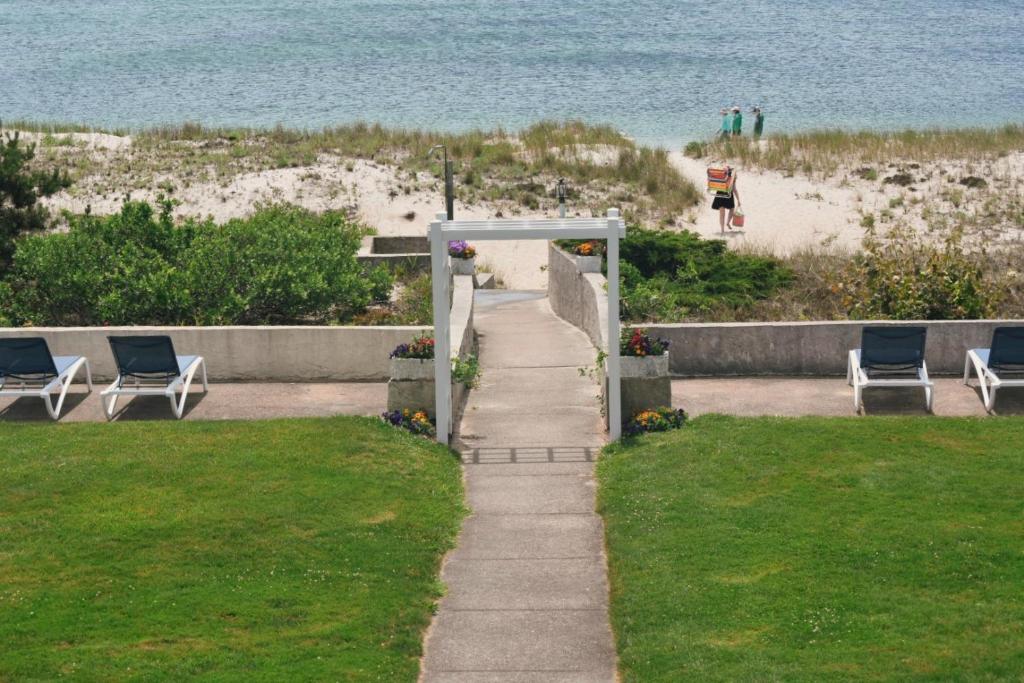 a pathway leading to a beach with chairs and the ocean at Surf & Sand Beach Motel in South Yarmouth