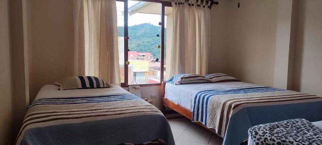 2 Betten in einem Zimmer mit einem großen Fenster in der Unterkunft LA CASA DE PASCUALA in Villa Rica