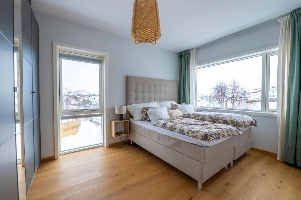 a bedroom with a bed and two large windows at Leilighet med sjøutsikt og privat takterrasse. Parkering in Svolvær