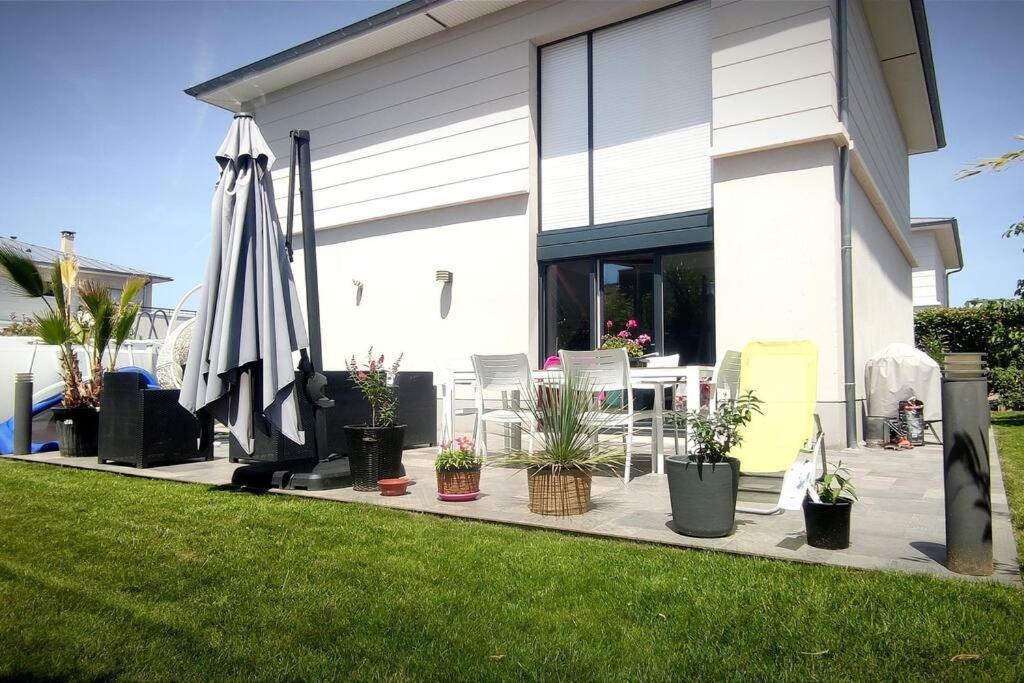 eine Terrasse mit einem Tisch, einem Sonnenschirm und Topfpflanzen in der Unterkunft Maison moderne proche site JO, Paris et Disneyland in Ferrières-en-Brie