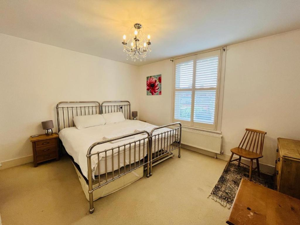 Schlafzimmer mit einem Bett, einem Fenster und einem Kronleuchter in der Unterkunft Luna Cottage - Grove Road Cottages in Stratford-upon-Avon