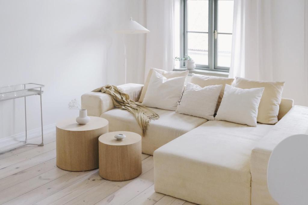 a white living room with a white couch and two tables at Avar ja hubane stuudiokorter kesklinnas in Viljandi