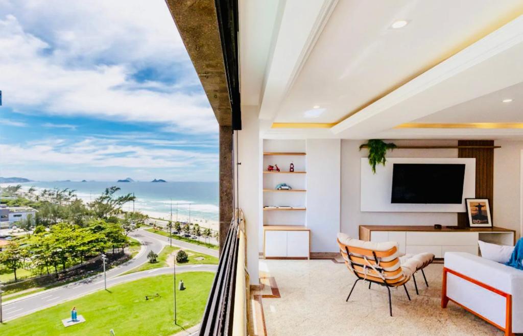 a room with a balcony with a view of the ocean at Maravilhoso apartamento na orla da Barra da Tijuca in Rio de Janeiro