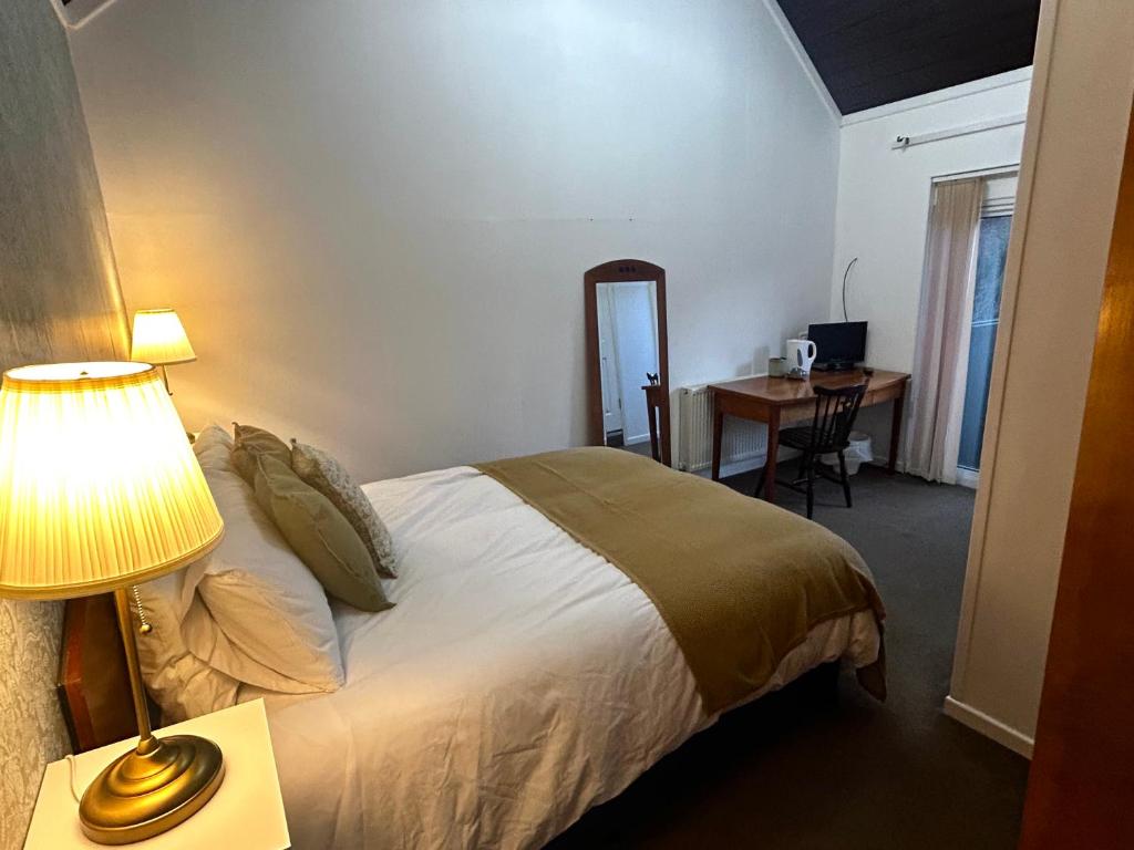 1 dormitorio con cama, mesa y escritorio en The Bulls Head, Clipston, en Clipston