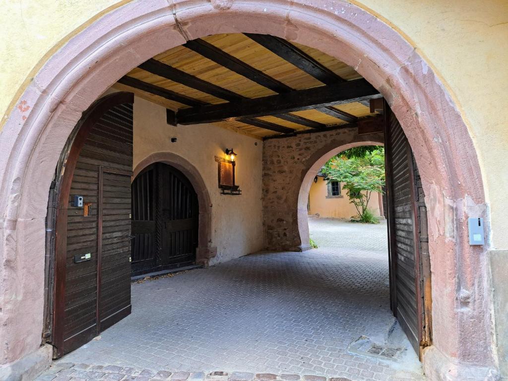 un accès voûté à un bâtiment avec deux portes brunes dans l'établissement Grand gîte dans maison alsacienne historique, à Gueberschwihr