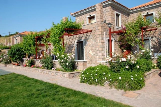 a brick house with flowers in front of a yard at Molivos Castle Apartments in Mythimna