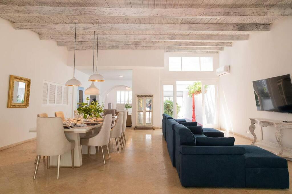 ein Wohnzimmer mit einem blauen Sofa, einem Tisch und Stühlen in der Unterkunft BLUE HOUSE - Beachfront Luxury House with 8 Bedrooms in Cartagena de Indias