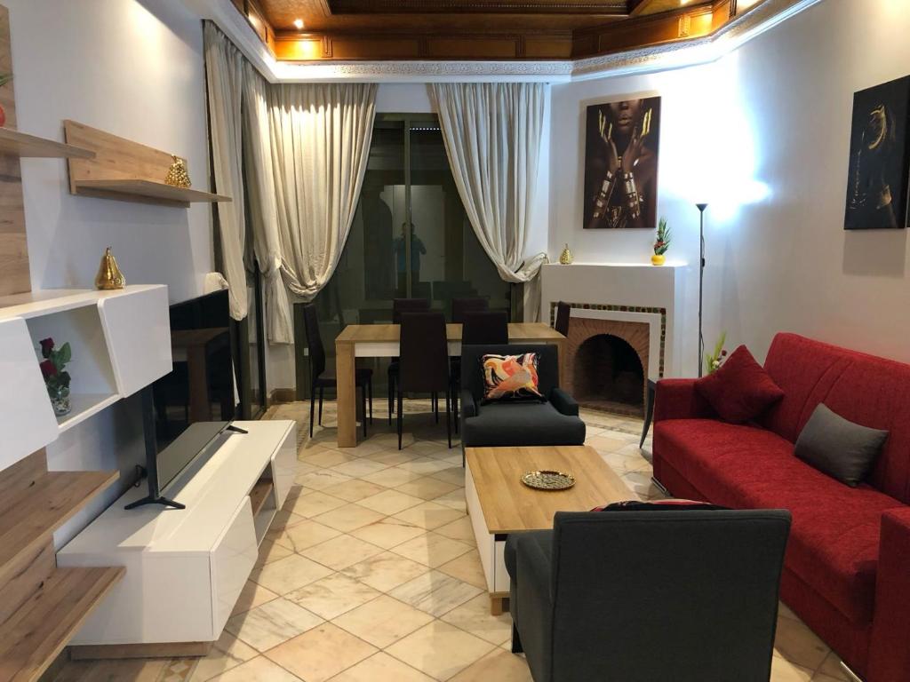 sala de estar con sofá rojo y mesa en Appartements de charme à la palmeraie en Marrakech