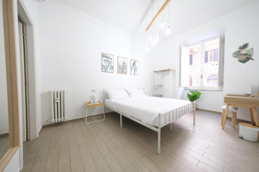a white bedroom with a bed and a window at Roman Forum Holiday Termini in Rome