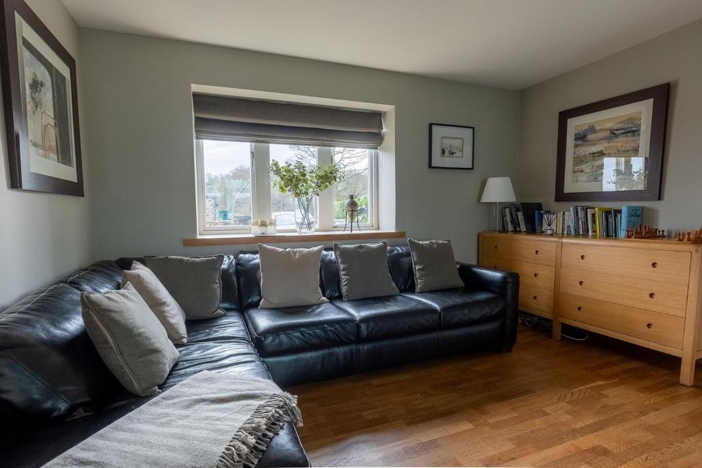 a black leather couch in a living room with a window at BIRDS EDGE COTTAGE - Luxury 2 Bedroom Cottage with Amazing Views, Near Holmfirth in Yorkshire in Denby Dale