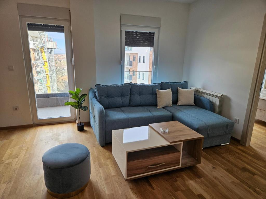 uma sala de estar com um sofá azul e uma mesa de centro em BELIV apartman em Stari Banovci