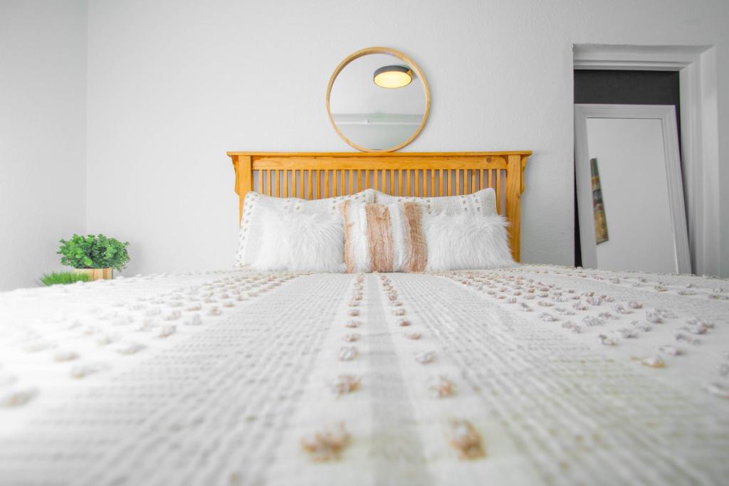 a white bed with a wooden headboard and a mirror at Vintage Elegance - Condo Steps Away from Casino in Hot Springs